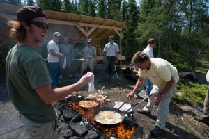 Guide cooking shorelunch while guests look on