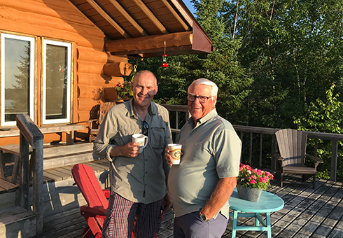 Two men enjoying coffee on the deck.