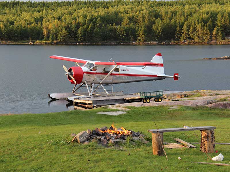 Float plane docked near a campfire.