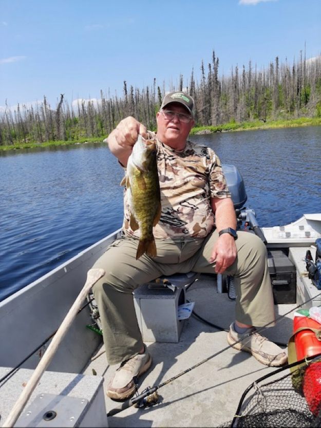 Man holding up a smallmouth bass in a boat