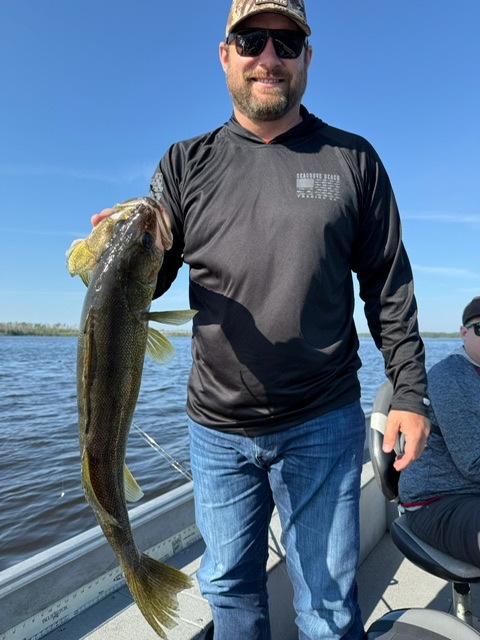 Man holding a walleye in a boat at Halley's Camps
