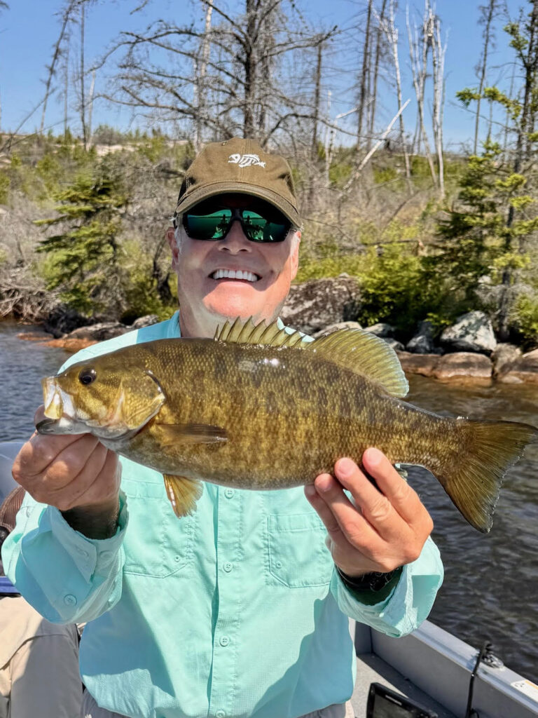 Man holding a large bass wearing a green shirt.