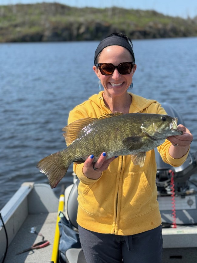 Woman smiling while holding a smallmouth bass