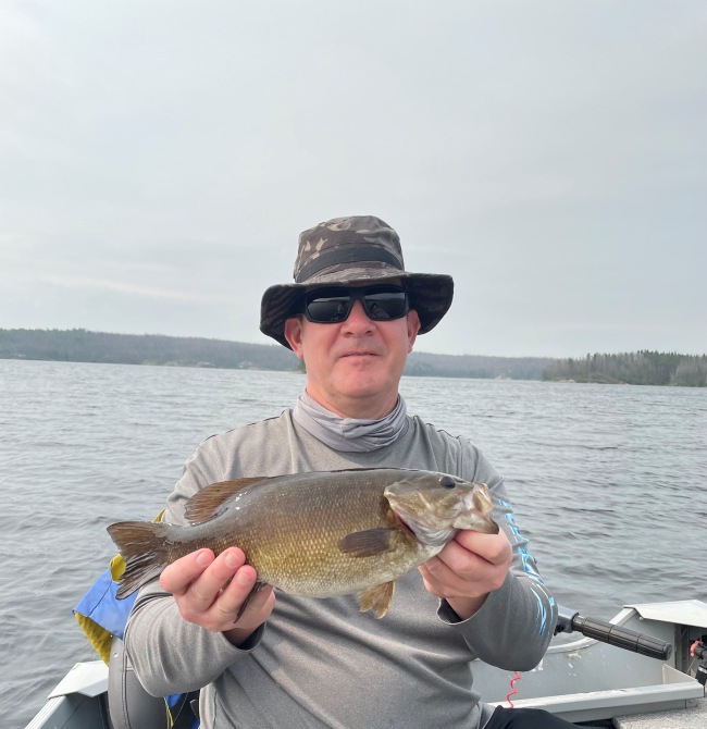 Man holding a fish in a boat on a smokey day.
