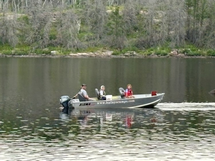 2 kids in a boat with dad driving the tiller boat