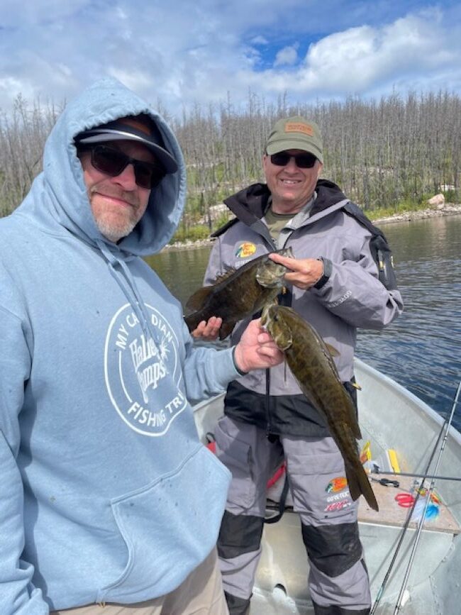2 men in a Halley's Camps boat in Canada holding 2 smallmouth bass