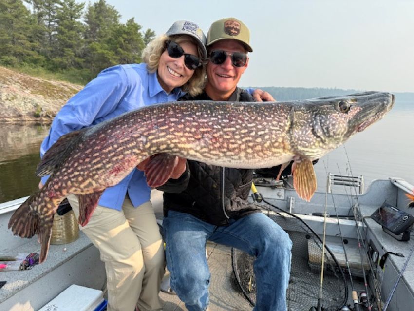 Woman and her fishing guide holding a fish in a boat