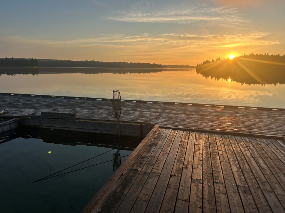 Scenery picture from the dock at Kettle Falls with the sun coming over the tree tops and the water is calm and flat