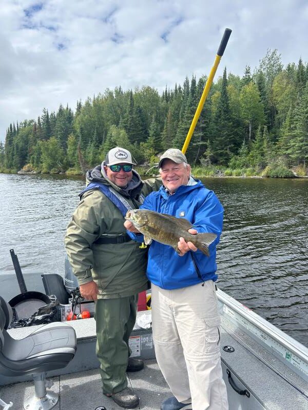 2 men standing in a boat holding a smallmouth bass at Halley's Camps