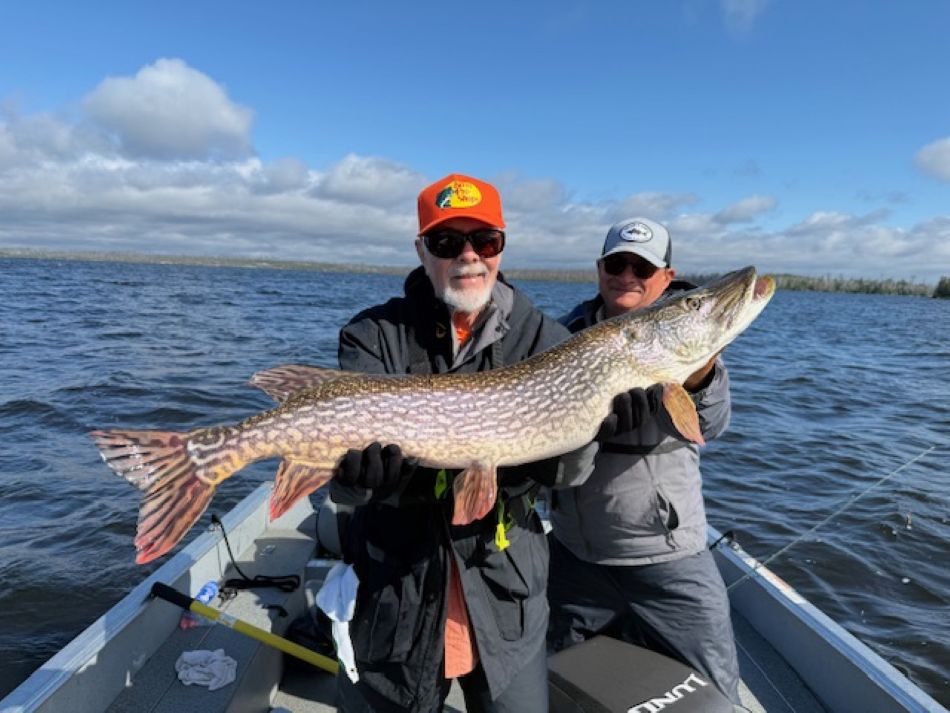 Main holding up a giant northern pike in a boat at Halley's Camps