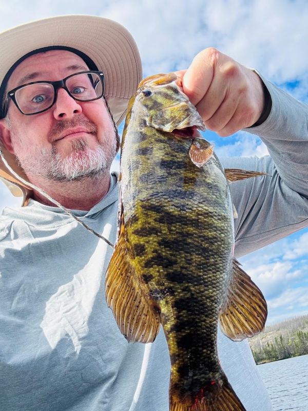 man holding a bass by the upper lip of the bas that has colorful stripes