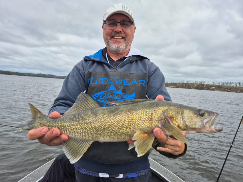 A guy fishing with his brother who was behind him in the boat goofing off while Tom is holding his fish and there is an extra hand in the picture
